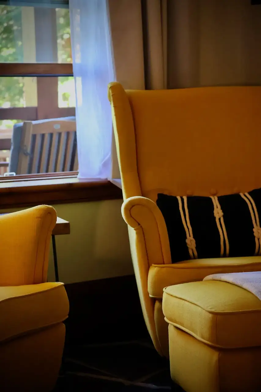 A mustard armchair by a window in a quiet guest room