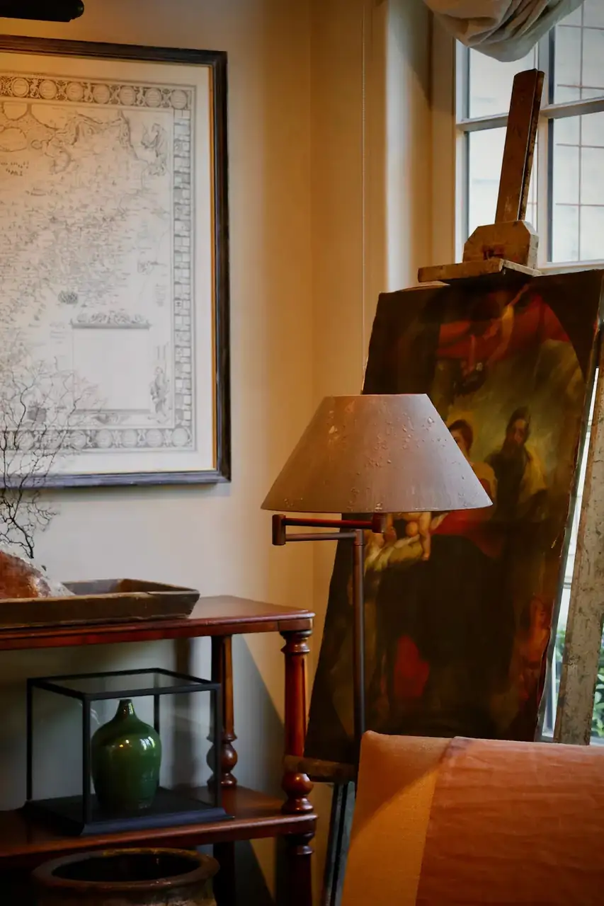 A lamp-lit reading corner with a map and paintings on the wall